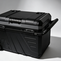 A rugged black hard-sided cooler with a carry handle, latches, and a small wheel, photographed on a clean light gray studio background.