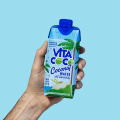 Hand holding Vita Coco coconut water carton with blue cap and tropical design